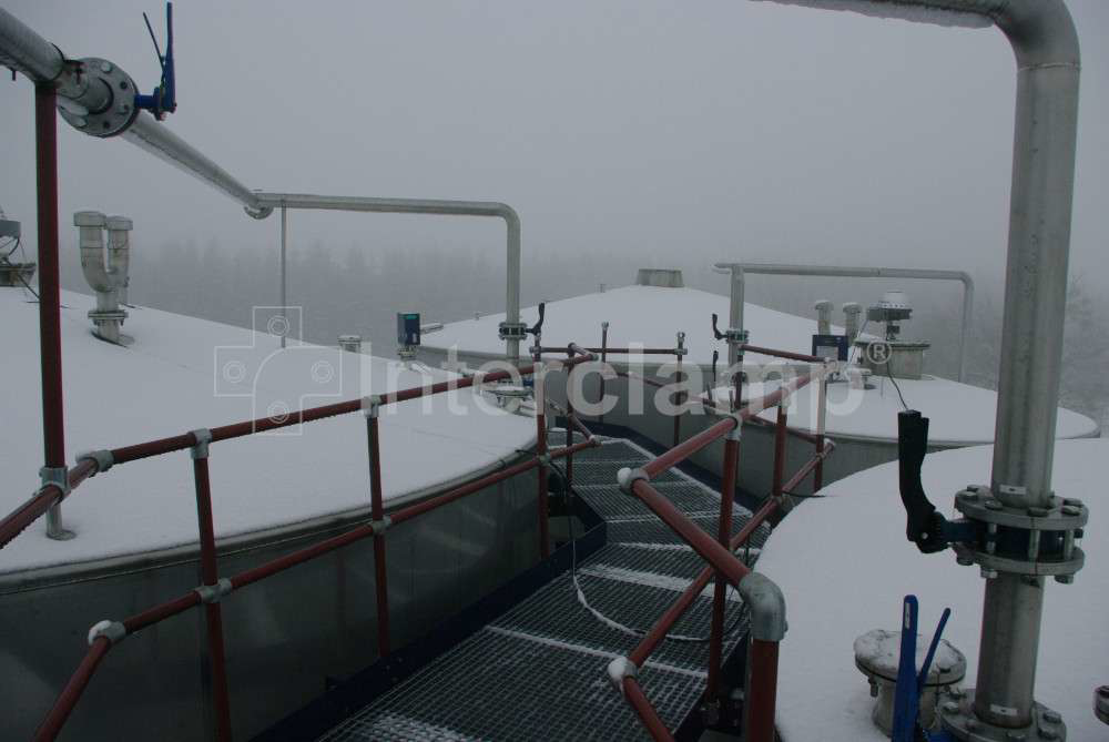 Workers walking along a chemical plant pathway secured by a safety guardrail constructed from Interclamp tube clamp fittings, ensuring their safety.